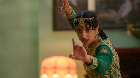 Actor Priya Kansara as the character Ria, wearing a gold-colored, beaded headband and anarkali dress and striking an action pose.